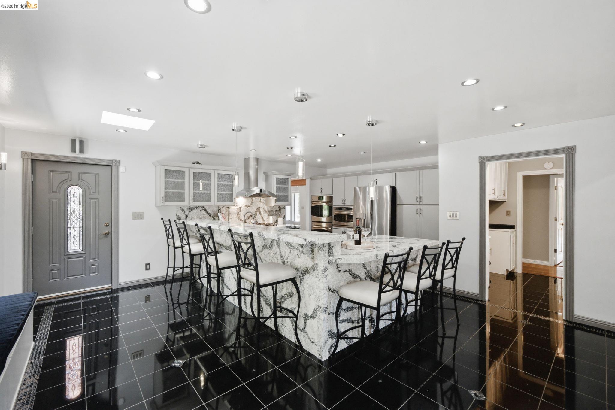 11133 Golf Links Road Oakland, CA 94605 - Photo 17 of 57 Spacious kitchen featuring a large waterfall-edge island, black tile flooring, recessed lighting, a skylight, and stainless steel appliances