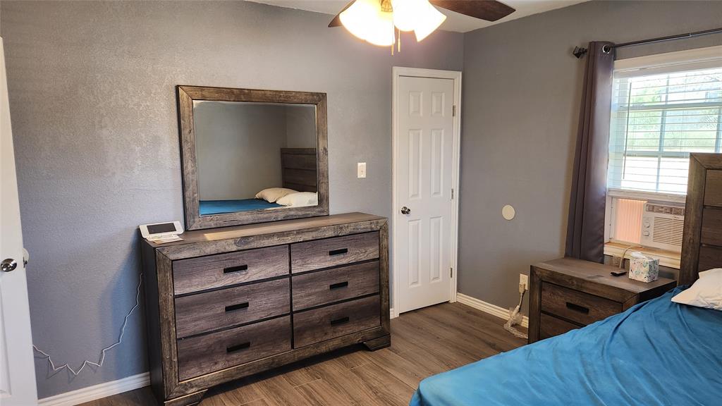 809 Bowie Street Sweetwater, TX 79556 - Photo 10 of 20 Bedroom with baseboards, wood finished floors, ceiling fan, and cooling unit