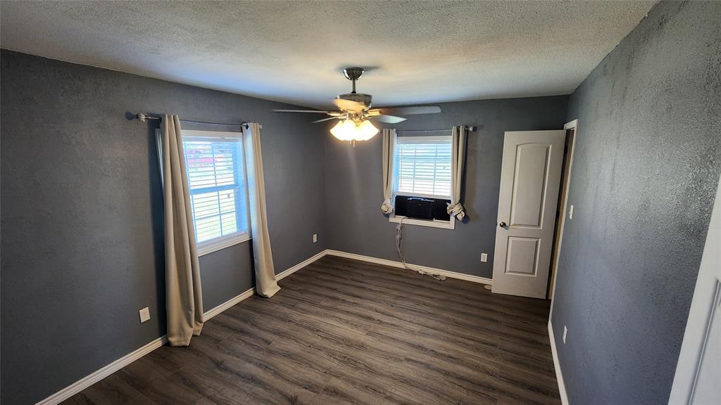 809 Bowie Street Sweetwater, TX 79556 - Photo 12 of 20 Spare room with dark wood-style floors, ceiling fan, a textured ceiling, cooling unit, and baseboards