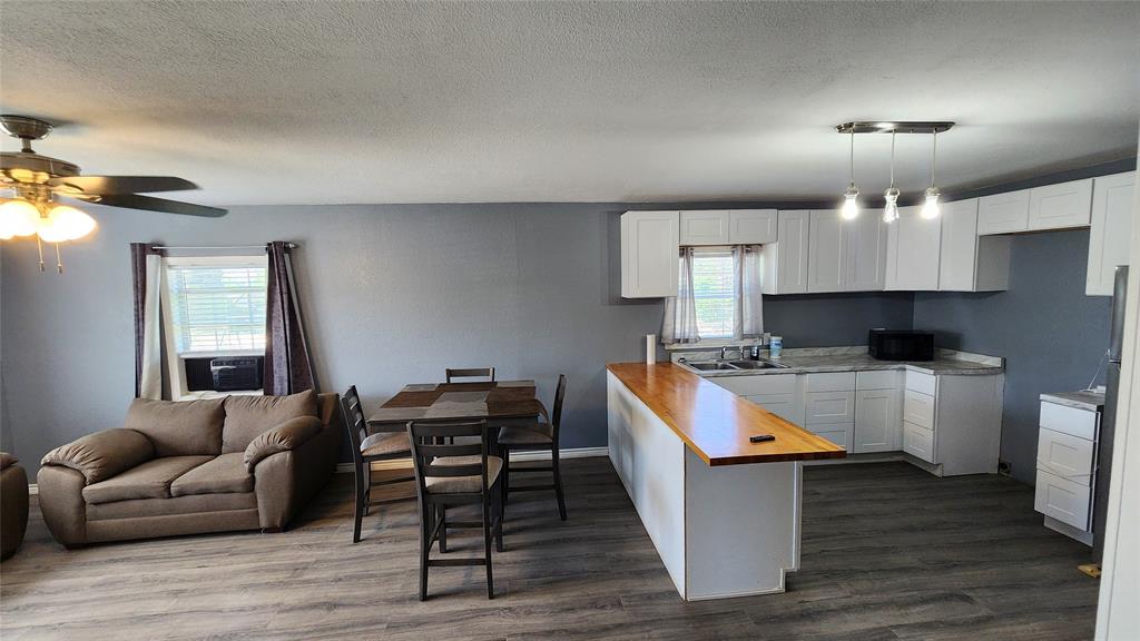 809 Bowie Street Sweetwater, TX 79556 - Photo 5 of 20 Kitchen featuring butcher block countertops, healthy amount of natural light, white cabinetry, and a textured ceiling