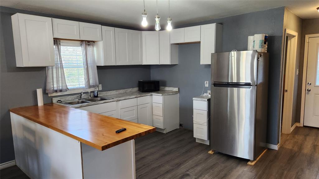 809 Bowie Street Sweetwater, TX 79556 - Photo 6 of 20 Kitchen featuring freestanding refrigerator, wood counters, a sink, dark wood-type flooring, and black microwave