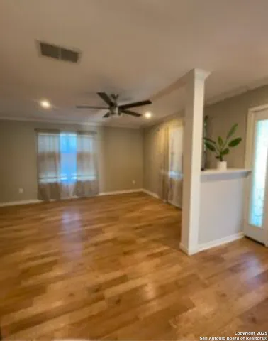 an empty room with wooden floor and windows