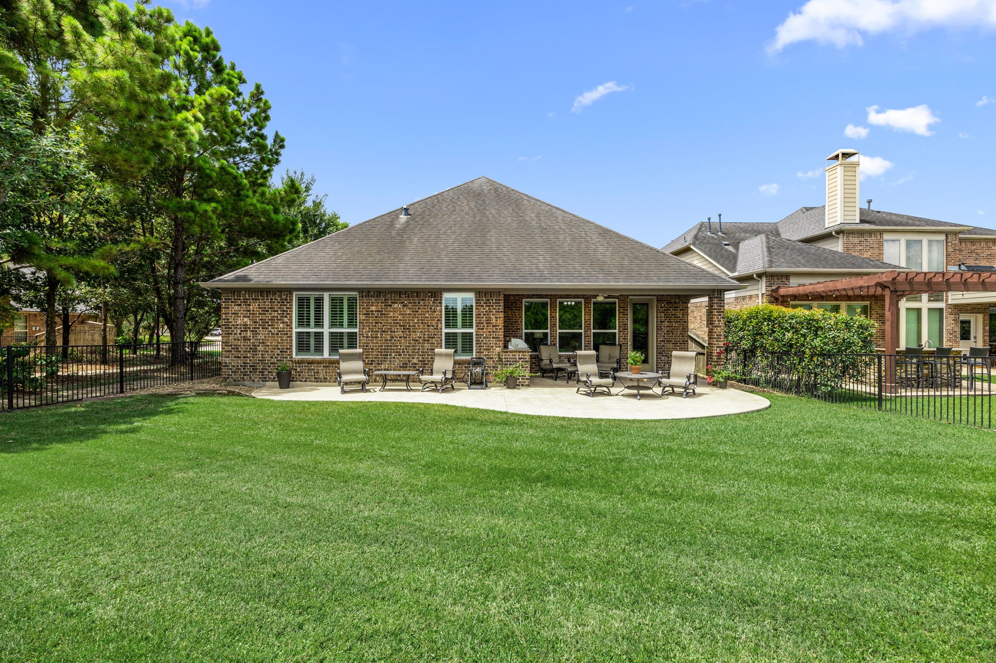 27642 Linden Ridge Lane Fulshear, TX 77441 - Photo 29 of 42 The Backyard is gorgeous and spacious, offering a fully fenced setting with a wrought iron fence that preserves open views while maintaining privacy. Expansive patio areas provide plenty of room to relax, entertain, and fully enjoy the peaceful surroundings and natural scenery.