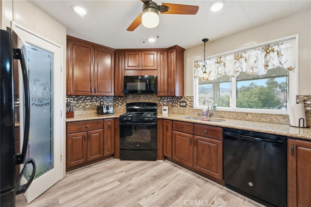 15181 Van Buren Boulevard, Unit 85 Riverside, CA 92504 - Photo 12 of 54 a kitchen with stainless steel appliances granite countertop a stove a sink dishwasher a refrigerator and a oven with wooden floor