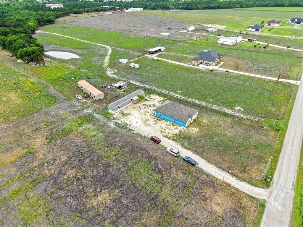 0 Ewing Road Ferris, TX 75125 - Photo 27 of 29 Expansive land parcel featuring a blue-sided structure with a gray shingle roof, accompanied by two long, light-colored outbuildings