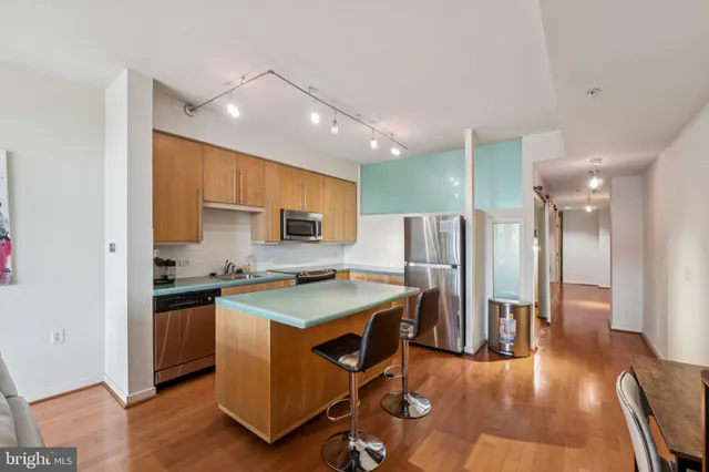 a kitchen with stainless steel appliances a stove a sink dishwasher a refrigerator white cabinets and wooden floor