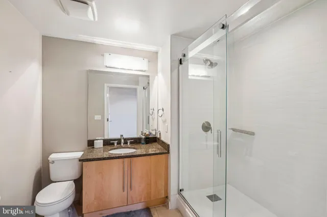 a bathroom with a granite countertop sink toilet and shower