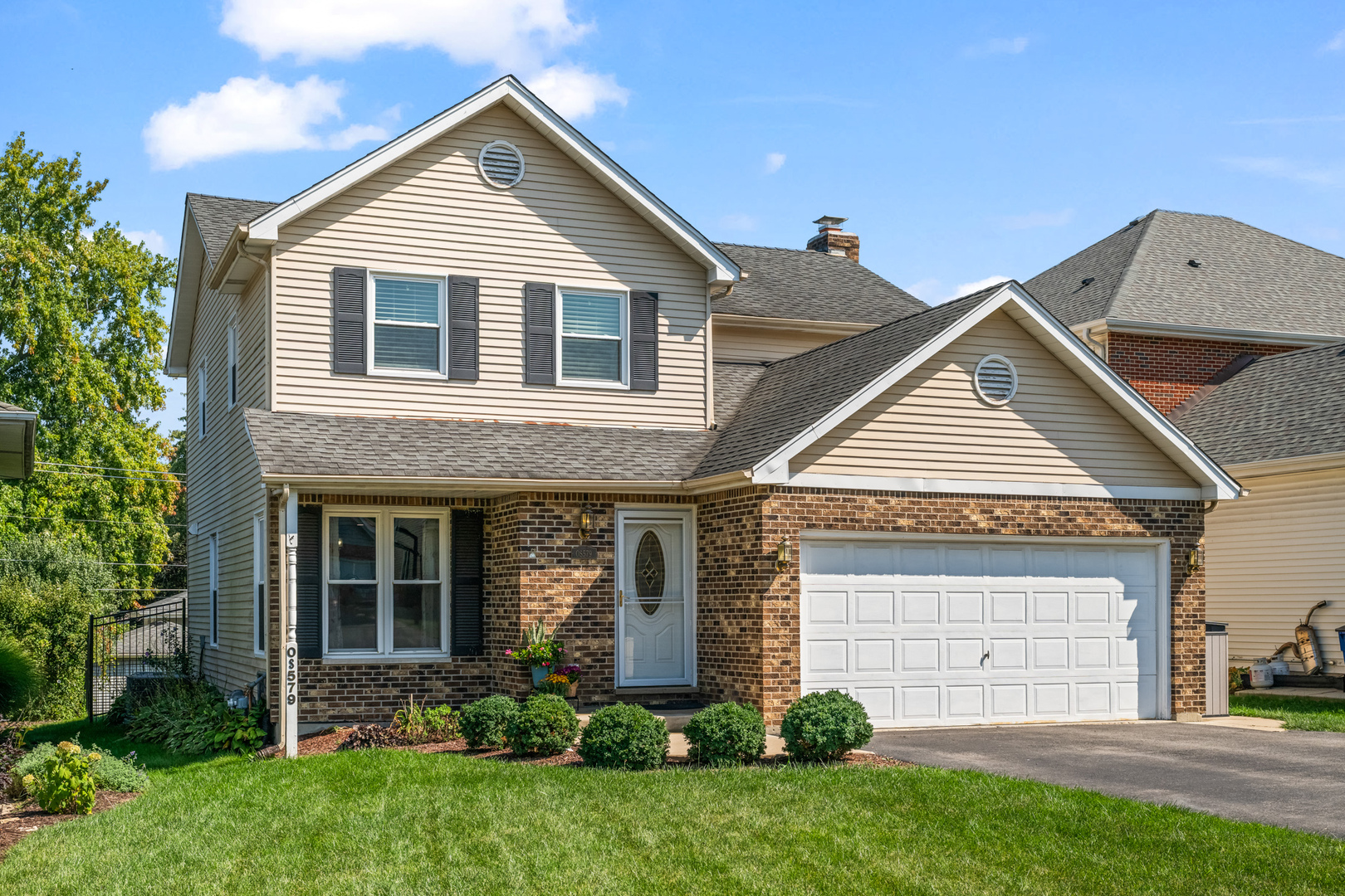 a view of a house with brick walls and a yard with plants