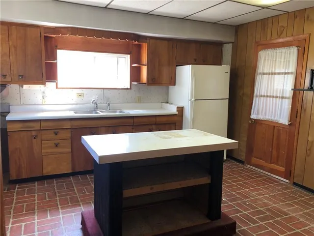a kitchen with a sink a refrigerator and wooden cabinets