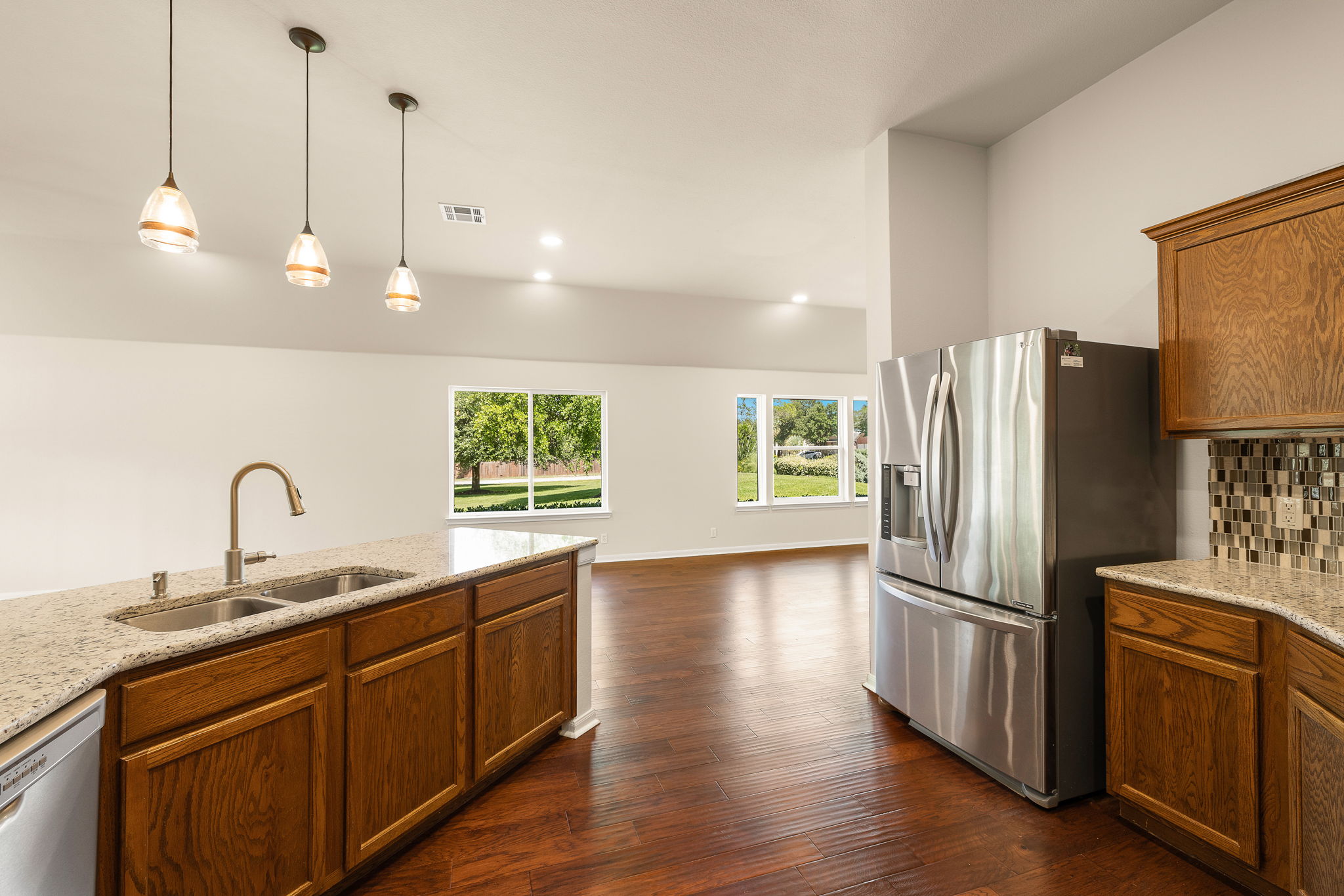 1100 Springbrook Road Pflugerville, TX 78660 - Photo 13 of 23 An open concept kitchen features warm wood cabinetry, granite countertops, and stainless steel appliances.