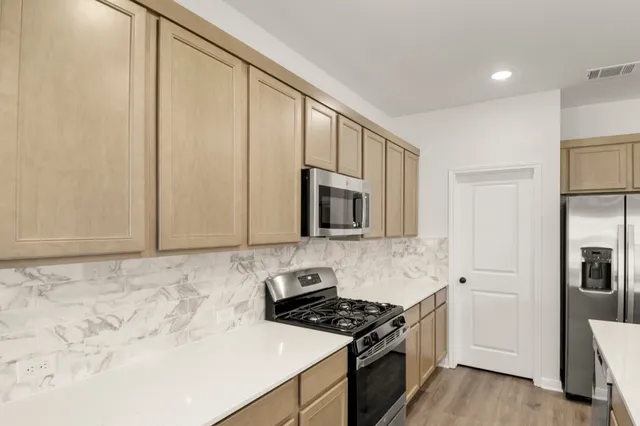 a kitchen with a refrigerator a microwave a sink and cabinets