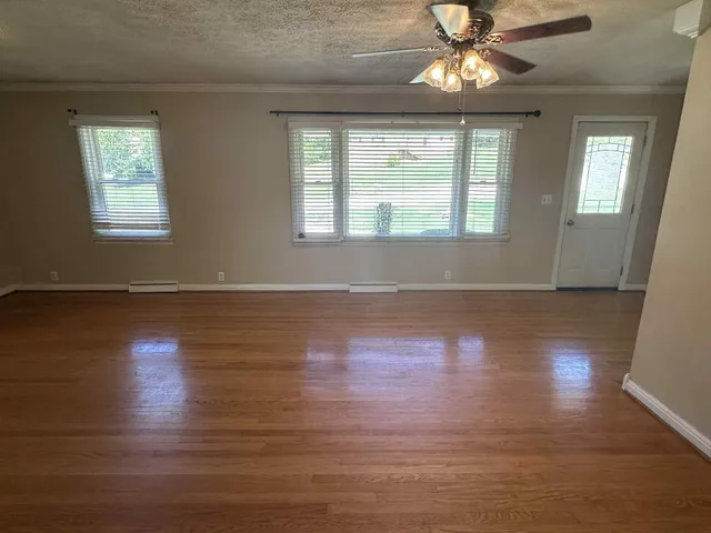a view of an empty room with wooden floor and a window