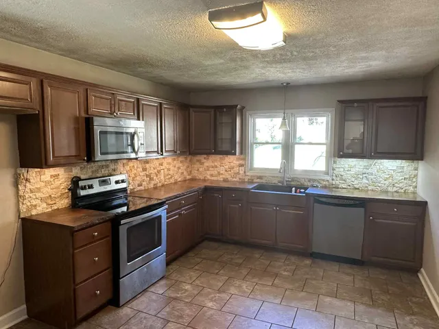 a kitchen with granite countertop a stove top oven microwave and cabinets
