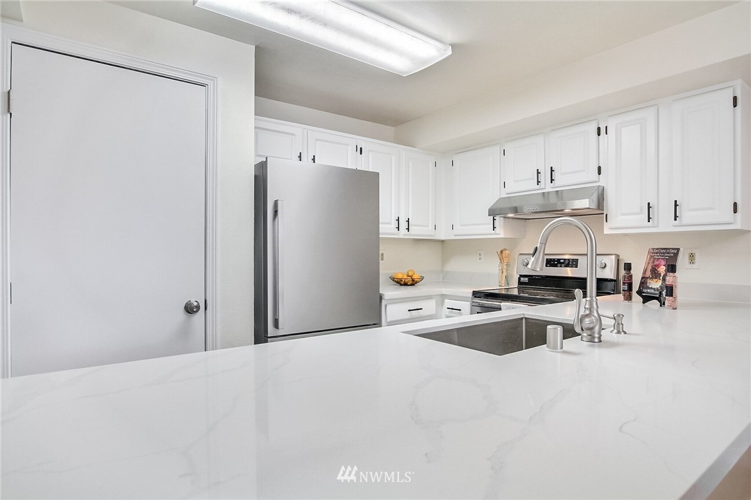 3939 10th Street Southeast, Unit A2 Puyallup, WA 98374 - Photo 11 of 27 a kitchen with stainless steel appliances granite countertop a refrigerator sink and white cabinets