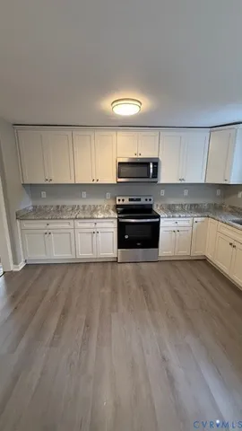 a kitchen with stainless steel appliances a stove a sink and white cabinets