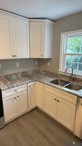 a kitchen with granite countertop white cabinets sink and window
