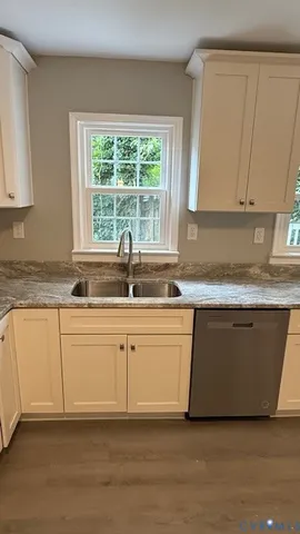 a white kitchen with granite countertop a sink window and a white cabinets