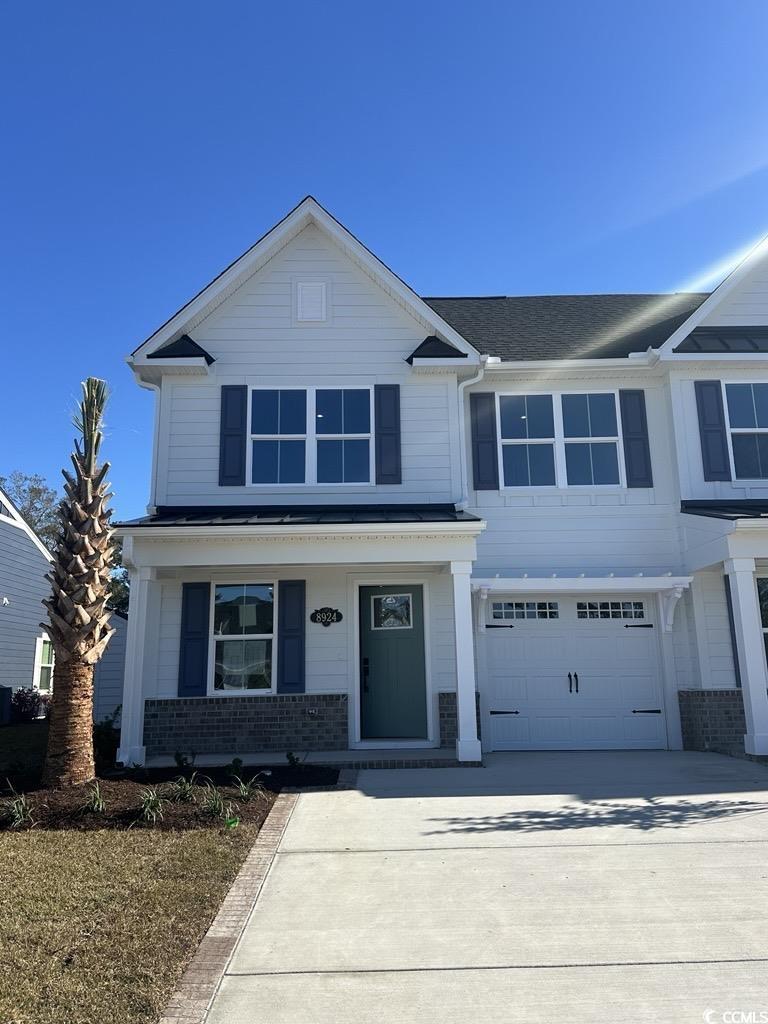 View of front facade with a porch, driveway, and an attached garage