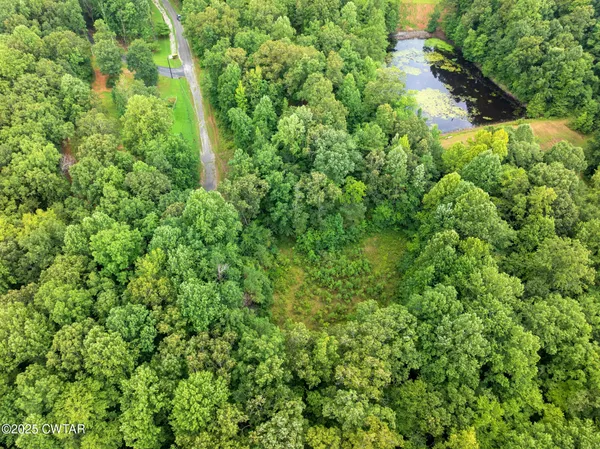 an aerial view of residential house with outdoor space and trees all around