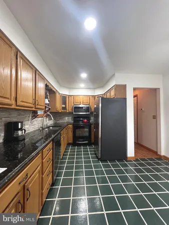 a kitchen with granite countertop a refrigerator a sink and dishwasher