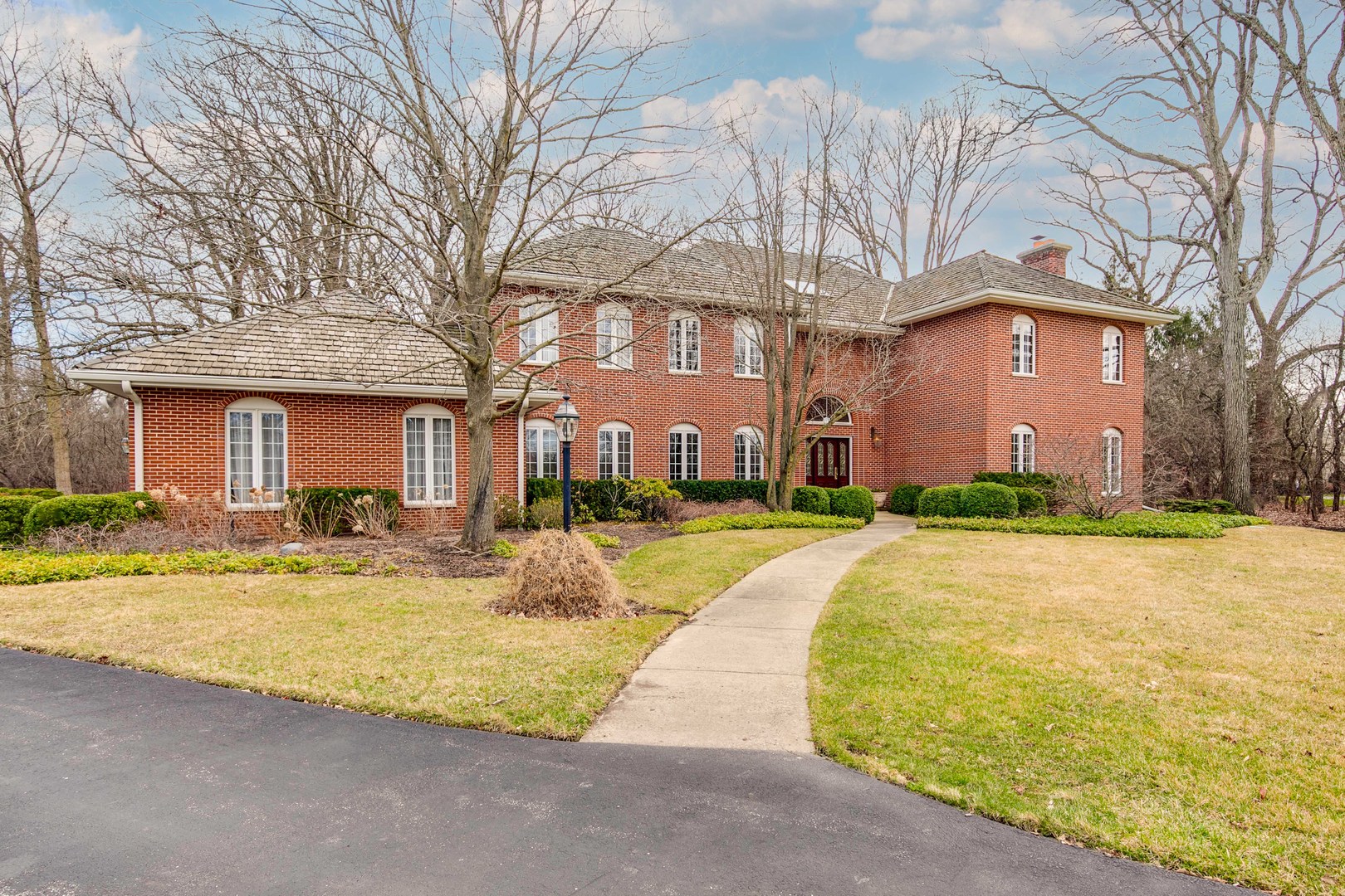 a view of a brick building next to a yard with large trees