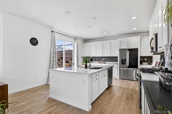 a kitchen with stainless steel appliances granite countertop a stove top oven a refrigerator a sink and dishwasher with wooden floor