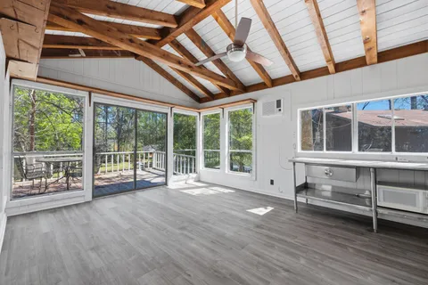 a view of an empty room with wooden floor and windows