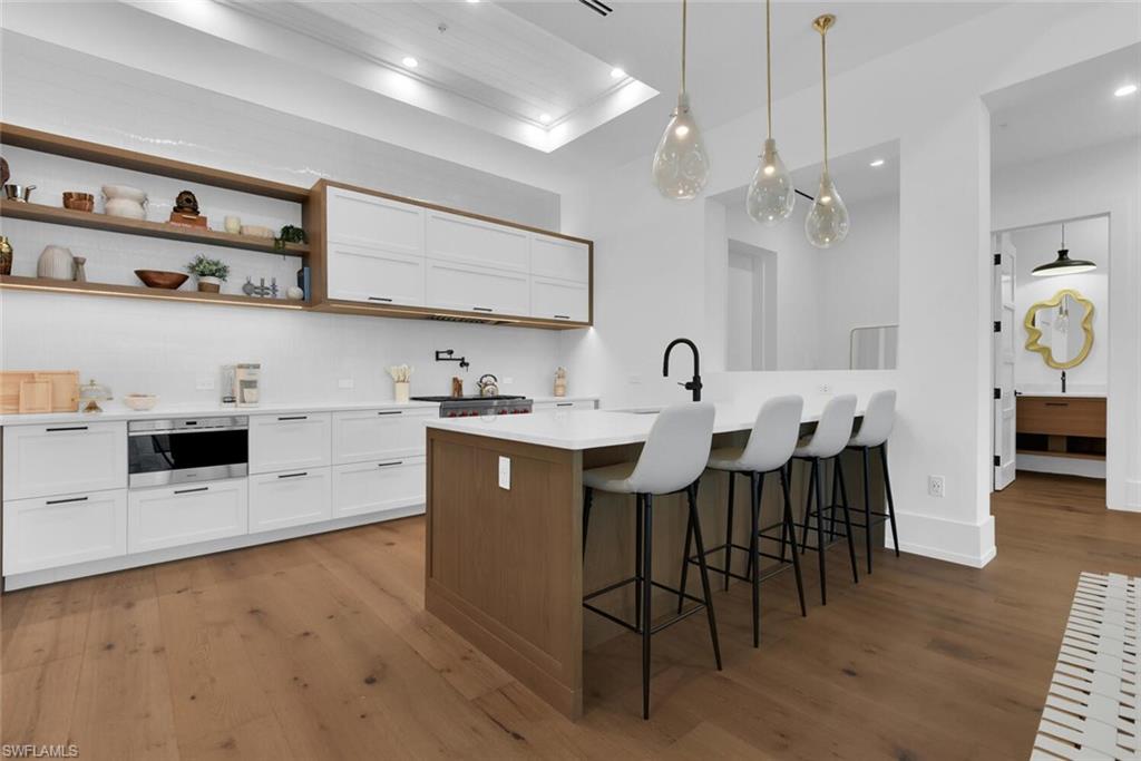 201 8th Street South, Unit 208 Naples, FL 34102 - Photo 12 of 46 a kitchen with stainless steel appliances a stove a sink a dining table and chairs with wooden floor