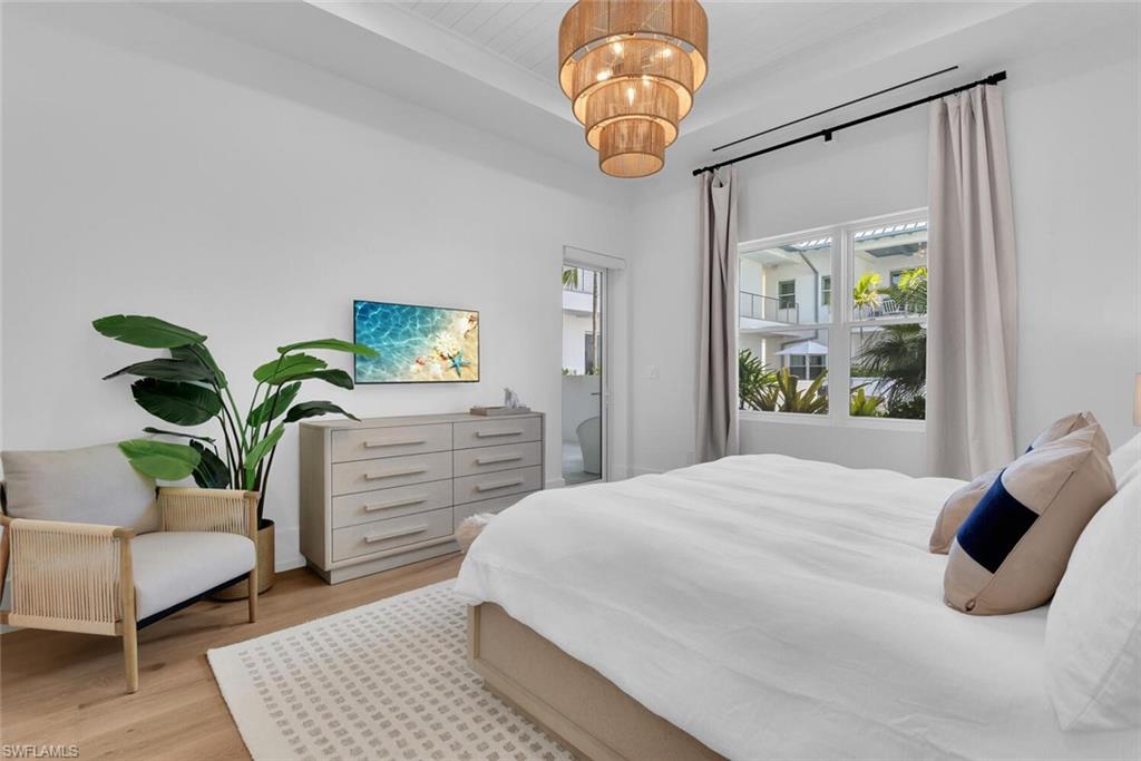 201 8th Street South, Unit 208 Naples, FL 34102 - Photo 15 of 46 a bedroom with a bed and a chandelier