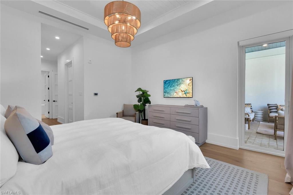 201 8th Street South, Unit 208 Naples, FL 34102 - Photo 16 of 46 a bedroom with a large bed and a chandelier