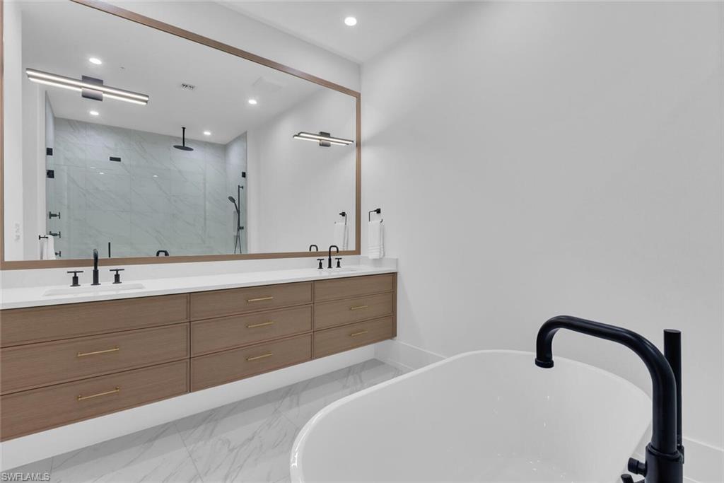 201 8th Street South, Unit 208 Naples, FL 34102 - Photo 17 of 46 a spacious bathroom with a double vanity sink a mirror and a bathtub