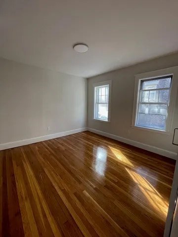 a view of empty room with window and wooden floor