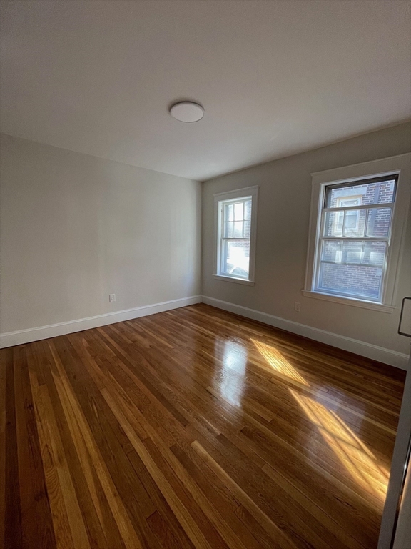 96 Walnut Street, Unit 2 Brookline, MA 02445 - Photo 11 of 13 a view of empty room with window and wooden floor