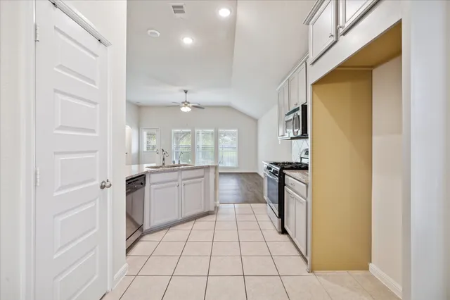 a large white kitchen with a stove a refrigerator and a sink