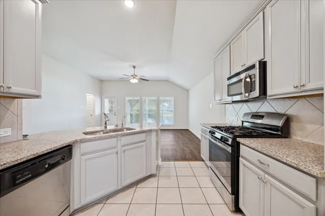 a kitchen with stainless steel appliances granite countertop a sink stove and cabinets