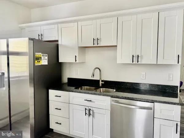 a kitchen with granite countertop white cabinets and refrigerator