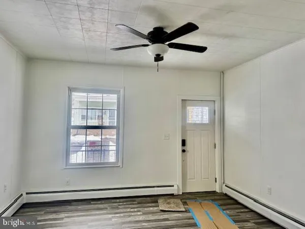 an empty room with wooden floor closet and windows