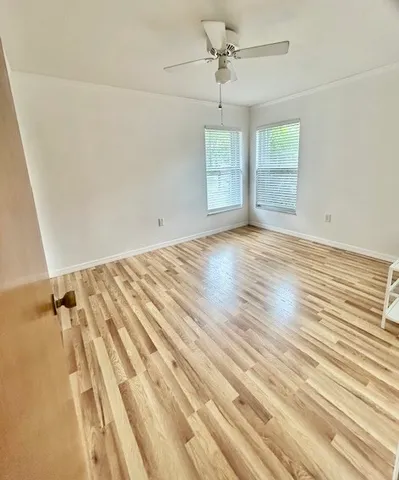 an empty room with wooden floor fan and windows