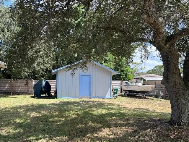 a front view of a house with a yard and a large tree