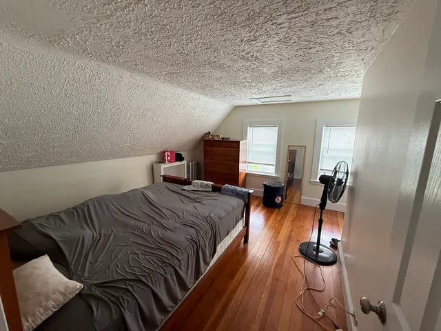 a bedroom with a bed and wooden floor