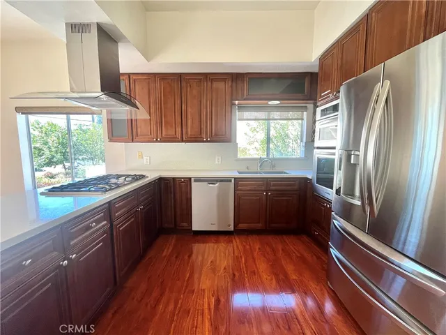a kitchen with stainless steel appliances wooden floors and wooden cabinets