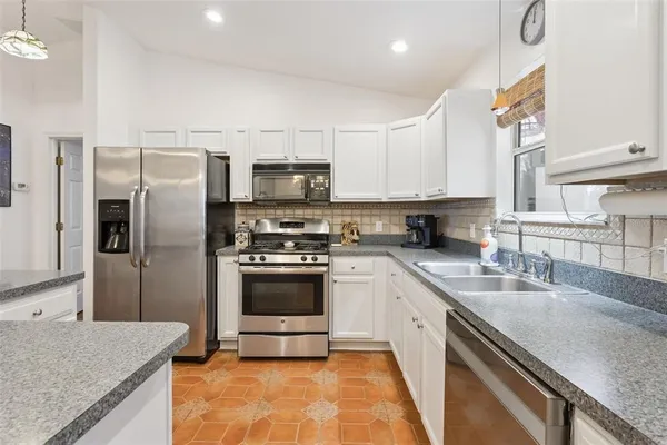 a kitchen with kitchen island granite countertop a sink stainless steel appliances and counter space