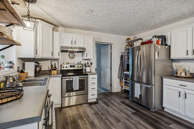 a kitchen with granite countertop a refrigerator stove and wooden floor