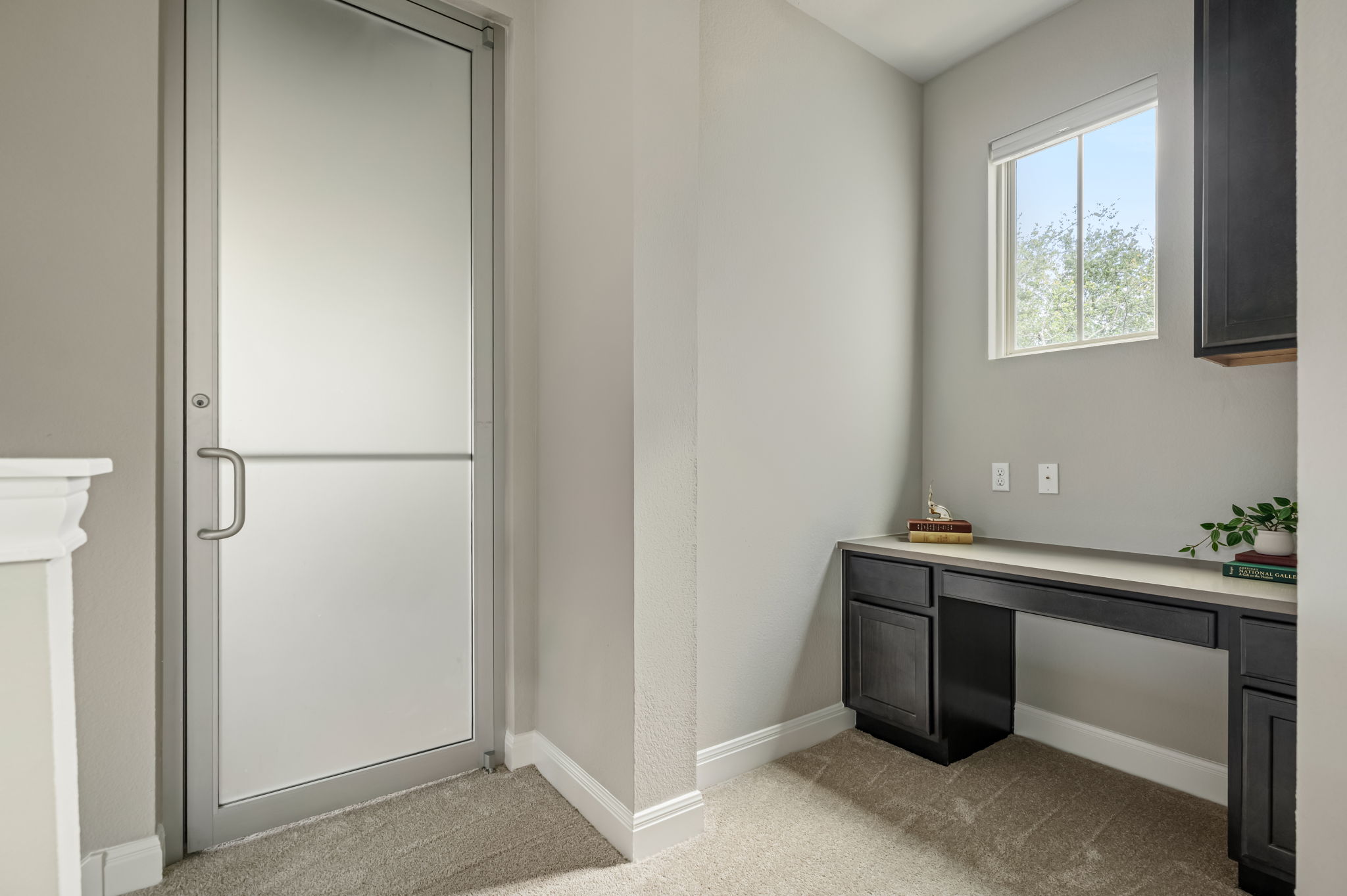 2516 Hopsack Mills Road Austin, TX 78748 - Photo 23 of 39 Frosted glass door with brushed metal hardware, built-in desk with dark cabinetry, light countertop, and a window with natural light
