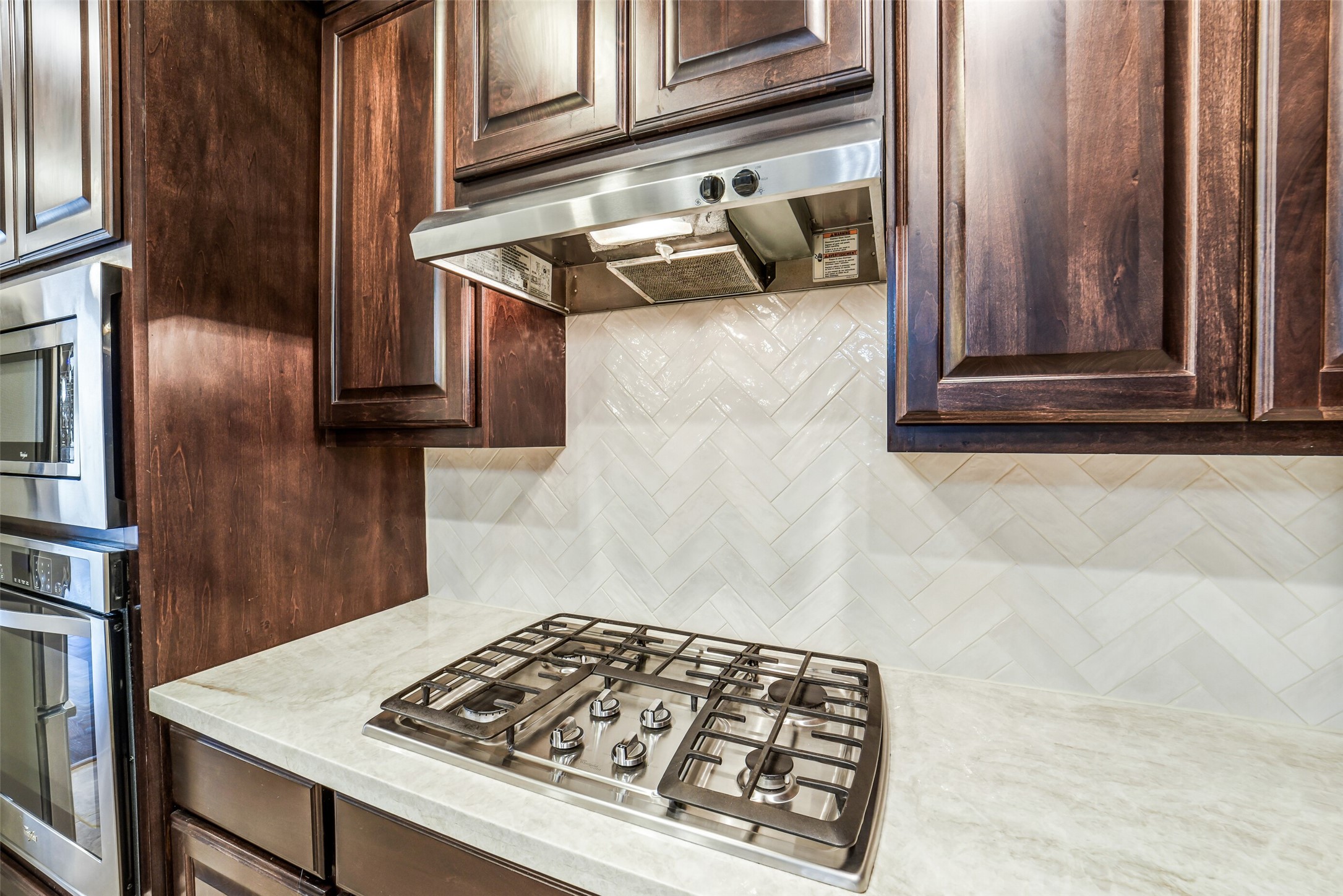 1303 Dorothy Street Houston, TX 77008 - Photo 7 of 21 A closer look at the gas cooktop with vent above. Note the new taj mahal countertops and decorative backsplash. To the left is a built in microwave and oven.