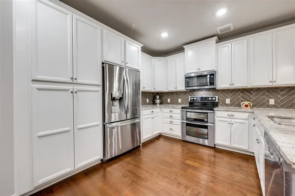 a kitchen with granite countertop white cabinets and stainless steel appliances