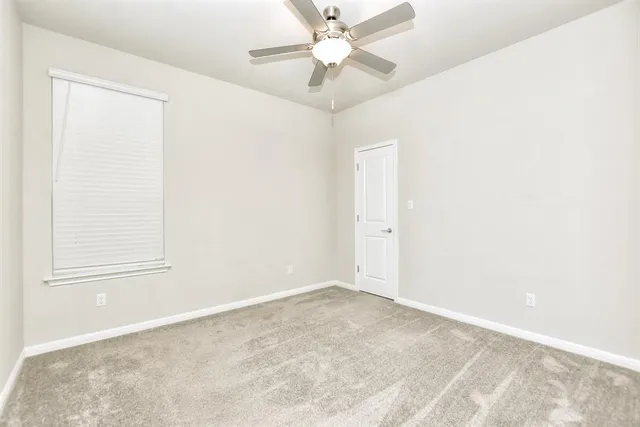 an empty room with a window and a fan