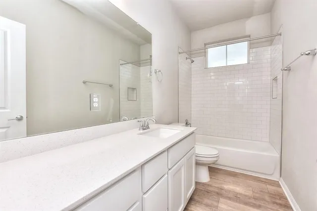 a bathroom with a granite countertop sink a toilet and shower