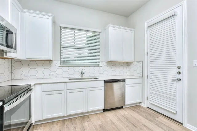 a kitchen with stainless steel appliances granite countertop white cabinets a sink and a window