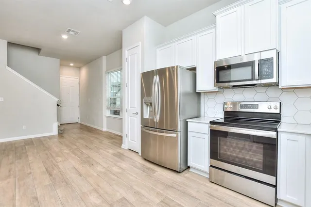 a kitchen with stainless steel appliances granite countertop a stove a refrigerator and a microwave